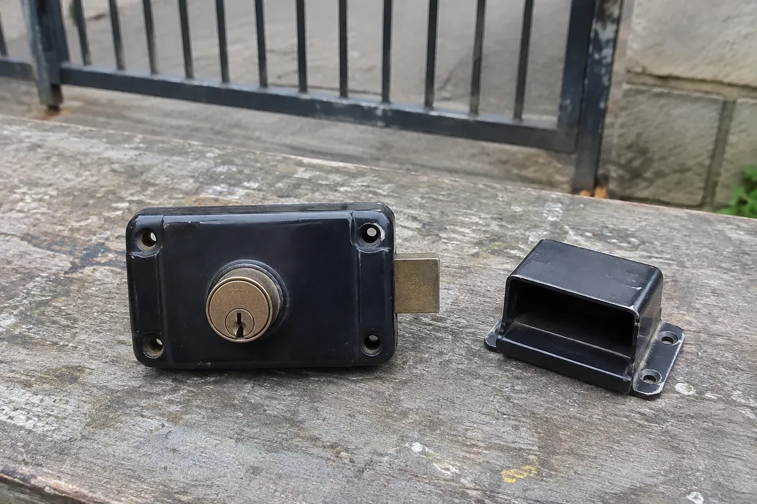 Detached rim gate lock and separate box keeper on an outdoor workbench. — Gate & Building Entry Locks, Innisfil