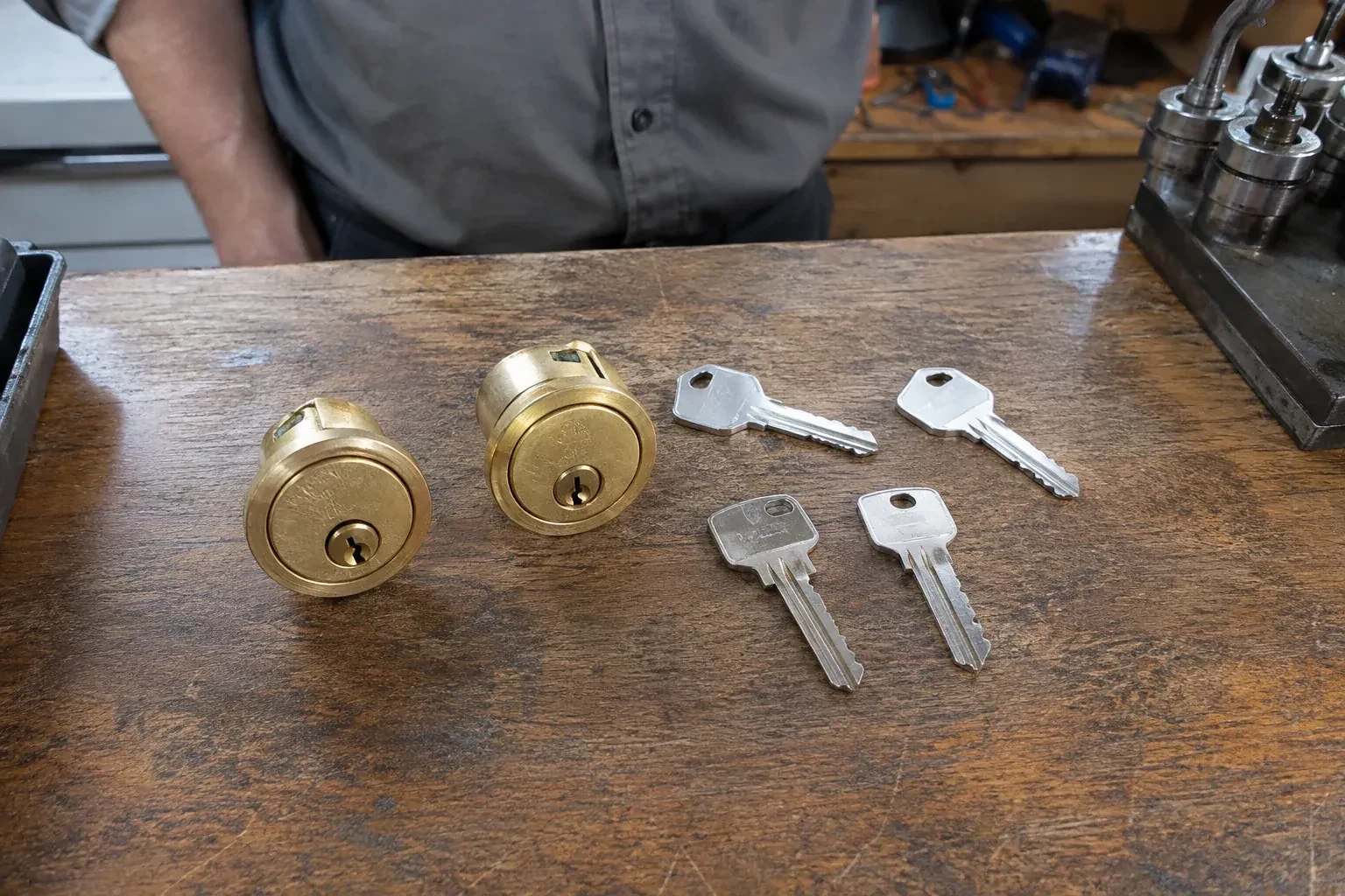 Two detached brass lock cylinders and four house keys on a wooden counter. — Lock Rekeying, Innisfil